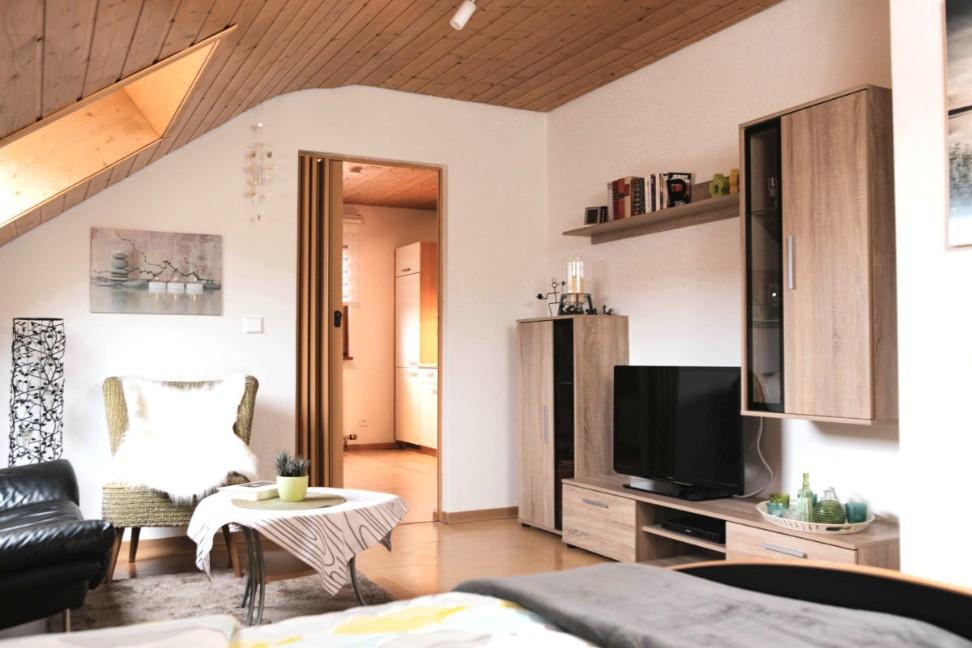 Wohnzimmer mit einer Schrankwand, Fernseher, Sessel und Couchtisch
